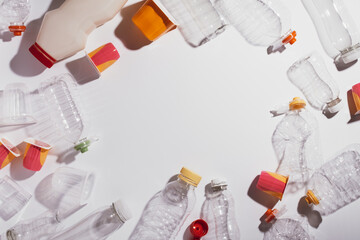 Frame with plastic waste scattered over white, theme of recycling, waste management