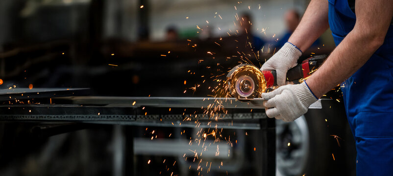 A man is cutting metal with a saw, wearing gloves - Powered by Adobe