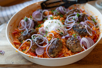 Cevapcici with spicy bell pepper rice in a frying pan