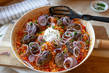 Cevapcici with spicy bell pepper rice in a frying pan