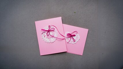 A close up of a pink card with a pink ribbon tied around it.