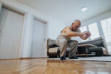 Fototapeta premium Elderly man working out in a home environment performing squats, emphasizing fitness, health, and an active lifestyle in a well-lit and inviting indoor space.