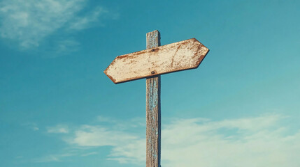 An aged wooden sign with directional arrows is fixed on a weathered pole against a vibrant blue sky.