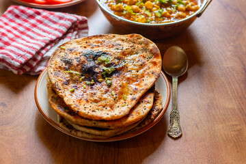 Amritsari kulcha is a crispy, flaky stuffed flatbread from Punjab, filled with spiced mashed potatoes or paneer, baked in a tandoor, and served hot with kabuli chana masala and salad
