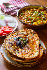 Amritsari kulcha is a crispy, flaky stuffed flatbread from Punjab, filled with spiced mashed potatoes or paneer, baked in a tandoor, and served hot with kabuli chana masala and salad
