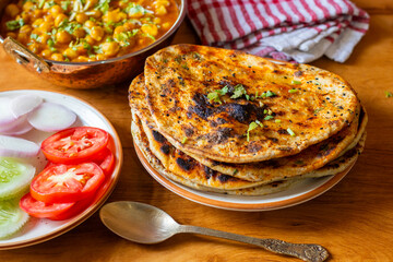 Amritsari kulcha is a crispy, flaky stuffed flatbread from Punjab, filled with spiced mashed potatoes or paneer, baked in a tandoor, and served hot with kabuli chana masala and salad
