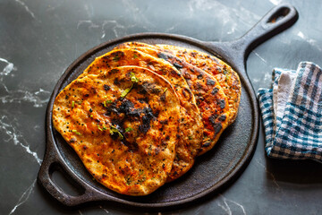 Amritsari kulcha is a crispy, flaky stuffed flatbread from Punjab, filled with spiced mashed potatoes or paneer, baked in a tandoor, and served hot with kabuli chana masala and salad
