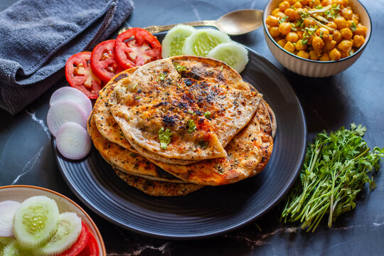 Amritsari kulcha is a crispy, flaky stuffed flatbread from Punjab, filled with spiced mashed potatoes or paneer, baked in a tandoor, and served hot with kabuli chana masala and salad
