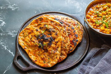 Amritsari kulcha is a crispy, flaky stuffed flatbread from Punjab, filled with spiced mashed potatoes or paneer, baked in a tandoor, and served hot with kabuli chana masala and salad
