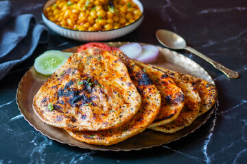 Amritsari kulcha is a crispy, flaky stuffed flatbread from Punjab, filled with spiced mashed potatoes or paneer, baked in a tandoor, and served hot with kabuli chana masala and salad
