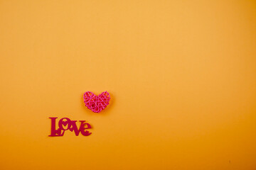 A minimalist stock photo featuring a pink heart and the word "LOVE" on an orange background, perfect for romantic and affectionate themes.