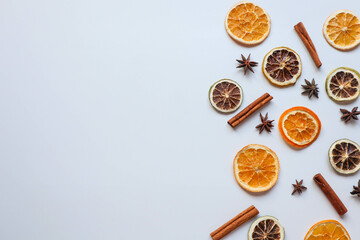 Slices of dried oranges, cinnamon sticks, and star anise are scattered across a white background, creating a festive arrangement