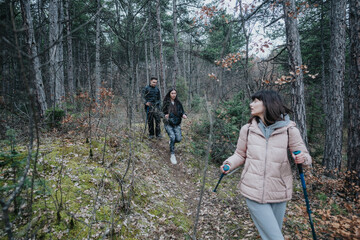 Friends walking through a serene forest, equipped for hiking and immersed in the peacefulness of...