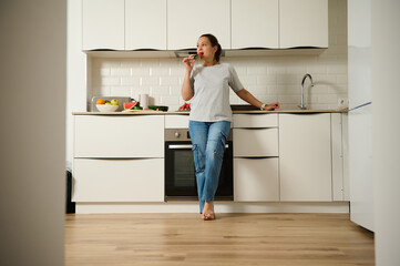 A casual moment in a clean, modern kitchen, featuring a woman enjoying snacks by the counter.