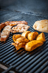 Juicy pork cuts and sausage on barbecue grill – close-up of sizzling BBQ feast. Selective focus.