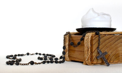 Dark rosary for prayers on a light background, yellow dried flower and wooden candlestick with white candle
