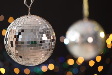 Shiny disco ball on black background with blurred lights
