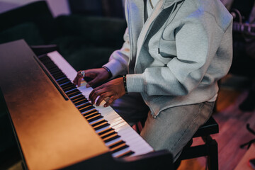 A close-up image of hands playing a piano, showcasing musical talent and relaxation. The casual...