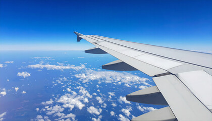 Obraz premium Airplane wing view above clouds with vibrant blue sky. Travel concept.