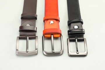 Three leather belts on white background, above view