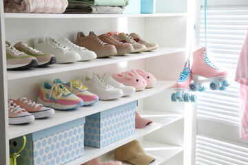 Different footwear and clothes on shelves indoors, closeup. Shoe storage