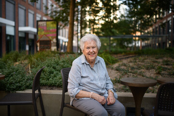 Portrait of beautiful old lady sitting outdoors in park.