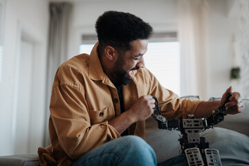 Handsome man holding small robot and dancing with it.