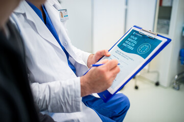 Close-up of doctor and teenage patient filling out mental health evaluation form.