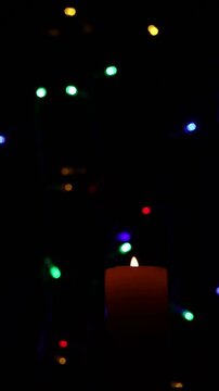 Una toma de cerca de una vela amarilla con llama rodeada de varias luces con bombillos de varios colores en movimiento en la oscuridad