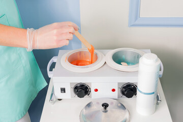 The process of heating the wax. The vessels contain melted orange and turquoise wax. Focus orange...