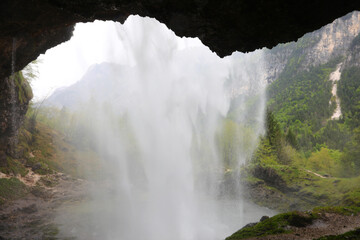 incredible view of water wall from behind a waterfall in the middle of the mountains