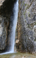 spend high waterfall with water gushing from the rocks above in an unspoiled environment