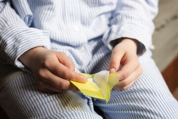 A woman holds a feminine hygiene pad in her hands, menstruation protection.