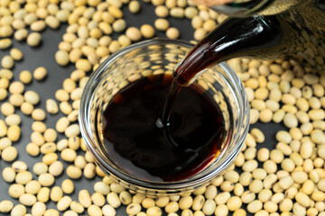 Close-up of the process of pouring soy sauce into a saucepan.