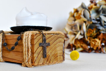 Dark rosary for prayers on a light background, yellow dried flower and wooden candlestick with white candle