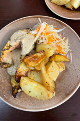 Delicious dinner in a cafe - baked potatoes, salmon in sauce and coleslaw or sauerkraut. View of food on a plate from above