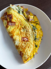 Fried frittata omelette with sausage and greens on white plate, close up. Protein breakfast at home or in cafe