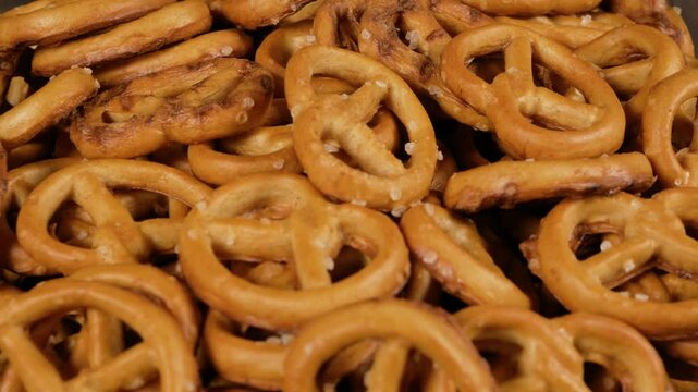 Pretzels in a glass bowl spinning against a black background. Close-up.