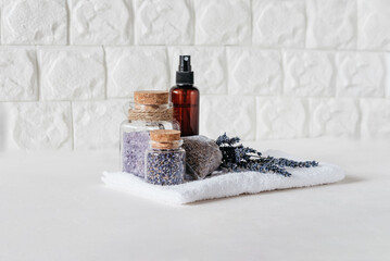 Lavender Spa Set with Dried Flowers and Bath Salts. Relaxing Spa Arrangement. Lavender flowers, bath salts, dried buds in glass jars, spray bottle, and sachet on white towel