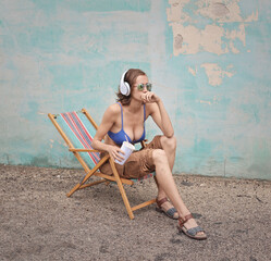 young woman in bikini sitting on a deck chair on the street