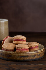 Vegan homemade French caramel macaroons with raspberry cream on shea butter on a wooden table. Sugar, lactose and gluten free. Vertical orientation.