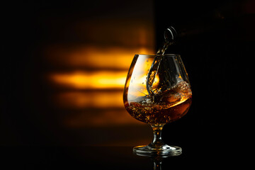 Pouring brandy from a bottle into a snifter.