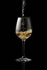 Pouring white wine into a glass on a black background.