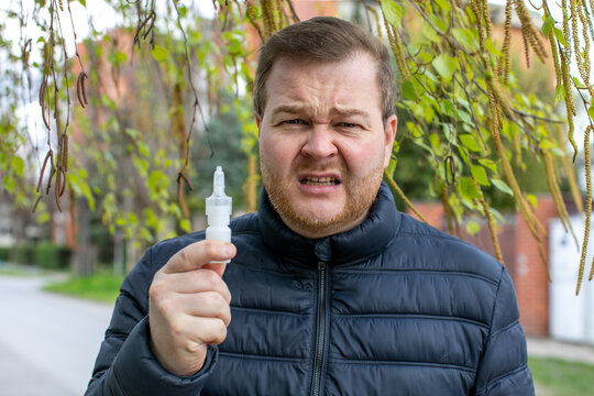 Burly Caucasian man outdoors with allergy relief spray amid pollen-filled breeze, capturing Springtime's floral cacophony and Allergy Awareness Week - Powered by Adobe