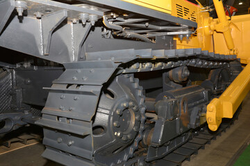 Close-up of the metal tracks of a yellow bulldozer.