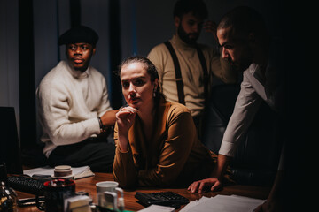 A group of professionals working together during a business meeting in dim lighting, fostering...