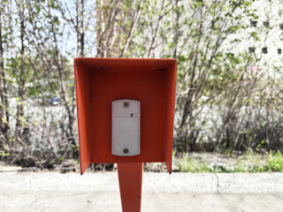 Bright orange mailbox standing outdoors in urban environment on a sunny day
