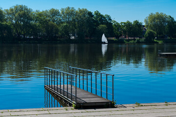 Calm lake view with dock and sailboat on a sunny day