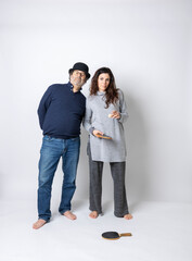 A handsome adult man and a beautiful adult woman stand barefoot against a white background with ping-pong paddles.