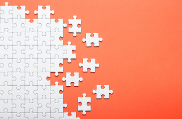 White Puzzle Pieces on Orange Background Representing Problem Solving